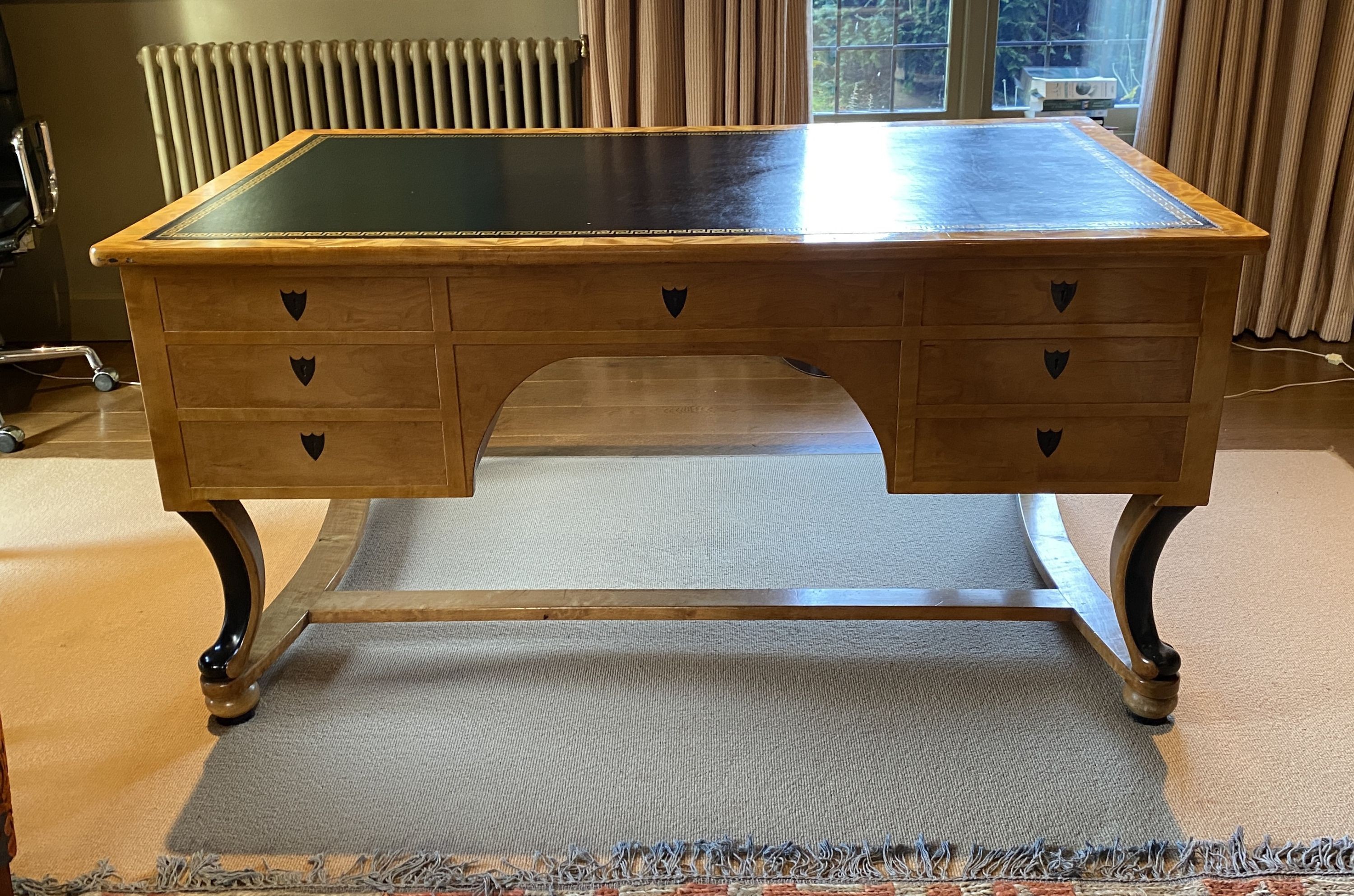 A Biedermeier style maple desk, with black leather skiver and seven drawers, on ebonised scroll legs with H stretcher, width 155cm depth 91cm height 76cm